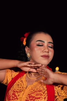 Close-up face of an Indonesian woman with makeup and an orange dress while wearing a piece of gold jewelry on her neck in the night