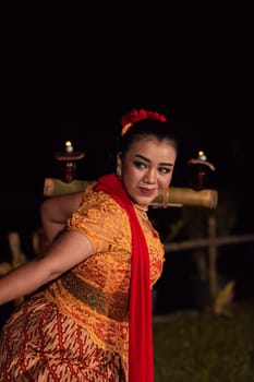 An Asian Traditional dancer in an orange dress with a red scarf and makeup performing at the dance festival in the night