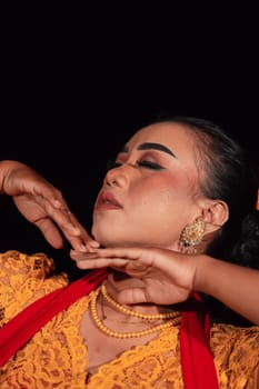 Close-up face of an Indonesian woman with makeup and an orange dress while wearing a piece of gold jewelry on her neck in the night