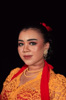 Javanese woman in a traditional orange dress while wearing makeup and a red scarf at a dance festival in Indonesia