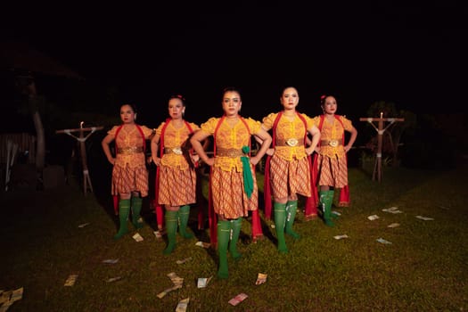 Balinese dancers standing together with red scarf and orange costumes on the stage after performing the traditional dance at the festival