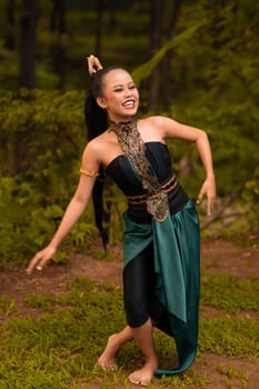 Indonesian woman with long black hair wearing a green costume with makeup in front of the forest during the festival