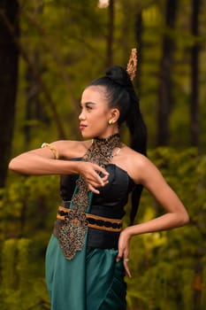 Beautiful Indonesian dancers with traditional green costumes and black tied hair posing inside the forest after performing