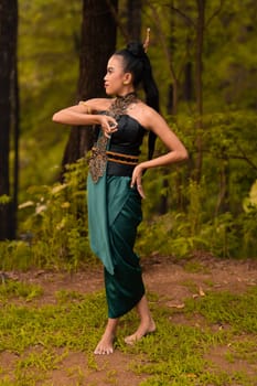 Beautiful Indonesian dancers with traditional green costumes and black tied hair posing inside the forest after performing