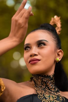 Portrait of a Balinese woman with beautiful makeup and tied black hair on a brave facial expression inside the jungle