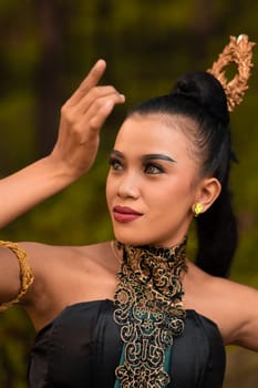 Portrait of a Balinese woman with beautiful makeup and tied black hair on a brave facial expression inside the jungle
