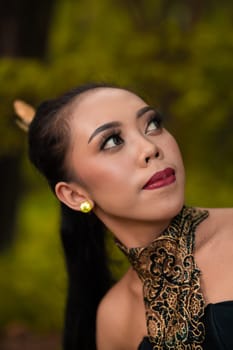 Balinese Woman wearing makeup with red lips while feeling sexy while wearing golden jewelry around her neck during the photo shoot