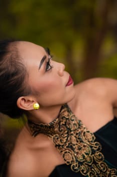 Balinese Woman wearing makeup with red lips while feeling sexy while wearing golden jewelry around her neck during the photo shoot