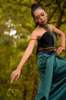 Indonesian woman dancing in the forest while wearing a traditional green costume during the festival inside the village
