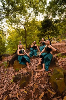 A Group of Asian women takes a vacation to the forest while wearing a green skirt and sitting on a rock during the morning
