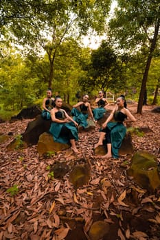 A Group of Asian women takes a vacation to the forest while wearing a green skirt and sitting on a rock during the morning
