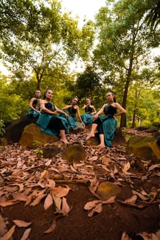 A Group of Asian women takes a vacation to the forest while wearing a green skirt and sitting on a rock during the morning