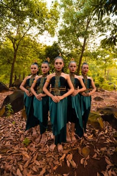 A Beautiful Asian woman in a green costume standing together in front of the forest with brown leaves in the background