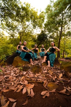A Group of Asian women takes a vacation to the forest while wearing a green skirt and sitting on a rock during the morning