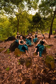 A Group of Asian women takes a vacation to the forest while wearing a green skirt and sitting on a rock during the morning