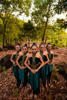 Glamor Asian women with green costumes and makeup line up together in the jungle with brown leaves on the ground