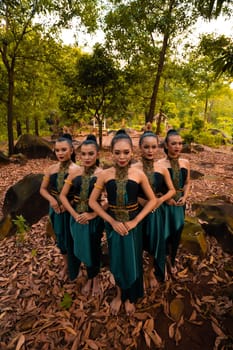 Glamor Asian women with green costumes and makeup line up together in the jungle with brown leaves on the ground