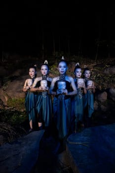 A Group of Balinese woman line up with the wooden mask in their hands while wearing a traditional dance costumes in the night