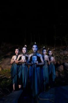 A Group of Balinese woman line up with the wooden mask in their hands while wearing a traditional dance costumes in the night