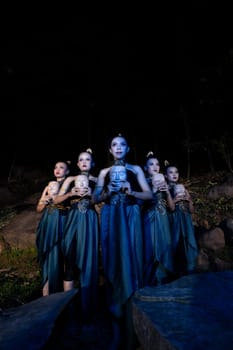A Group of Balinese woman line up with the wooden mask in their hands while wearing a traditional dance costumes in the night