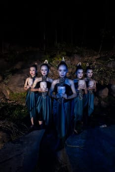 A Group of Balinese woman line up with the wooden mask in their hands while wearing a traditional dance costumes in the night