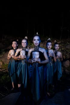 A Group of Balinese woman line up with the wooden mask in their hands while wearing a traditional dance costumes in the night