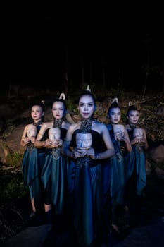 A Group of Balinese woman line up with the wooden mask in their hands while wearing a traditional dance costumes in the night