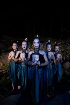A Group of Balinese woman line up with the wooden mask in their hands while wearing a traditional dance costumes in the night