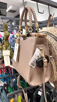 Ottawa, ON Canada - May 01, 2025: Elegant beige handbag featuring braided handles is showcased on a retail display rack, surrounded by colorful accessories, contemporary fashion trends for shoppers