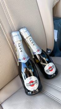 Miami, FL USA - February 05, 2025: Two bottles of MARTINI and ROSSI Asti sparkling wine placed on a luxurious beige leather car seat, showcasing elegance and sophistication during picknic.