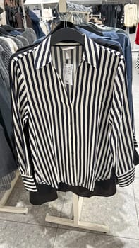 Ottawa, ON Canada - February 01, 2025: A stylish striped blouse hanging on a retail display, featuring a navy and white pattern, representing fashion trends and appealing to modern women's clothing choices