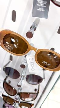 Ottawa, Canada - May 01, 2025: Trendy brown sunglasses are prominently featured on a retail display shelf, emphasizing the UV protection label, perfect for summer fashion and outdoor activities