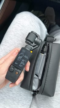 Ottawa, Canada - April 05, 2025: A hand grips a DJI Osmo Pocket 3 camera, resting on a lap with a sleek black carrying case, highlighting innovative design for capturing steady videos