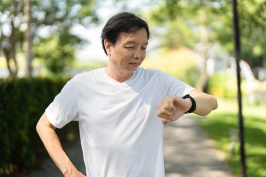 A man evaluates his fitness metrics on a smartwatch after exercising in a park, promoting a healthy lifestyle.