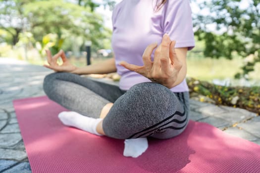 A woman sits in a yoga pose, meditating by a tranquil lake, embracing wellness and mindfulness.