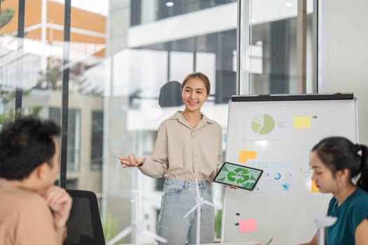 A professional woman presents ESG strategies to her team in a modern office, highlighting sustainability and business growth.
