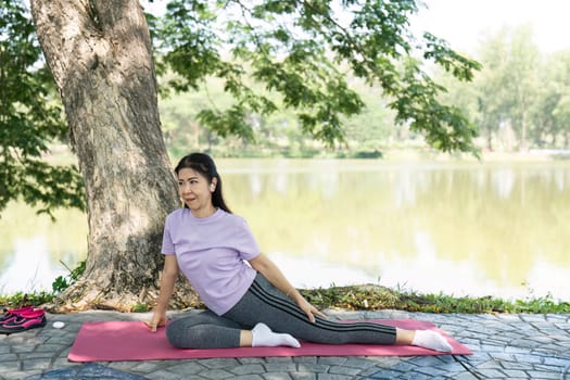A woman performs yoga stretches outdoors, enhancing her wellness and fitness routine amidst a calm natural setting.