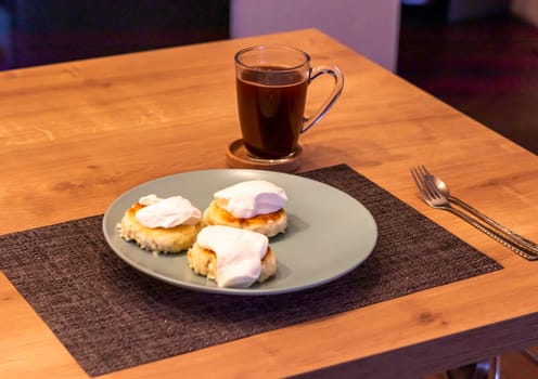 Traditional russian breakfast cheese cakes or syrniki made of cottage cheese on the plate next to cup of cofee