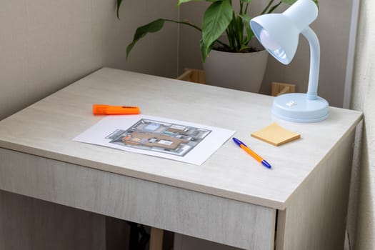 Layout of the small, furnished apartment printed on the sheet of paper placed on the desk