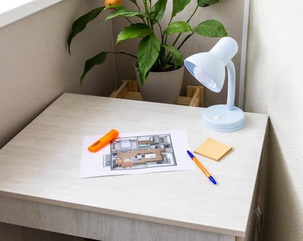 Layout of the small, furnished apartment printed on the sheet of paper placed on the desk