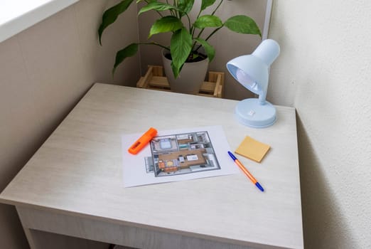 Layout of the small, furnished apartment printed on the sheet of paper placed on the desk