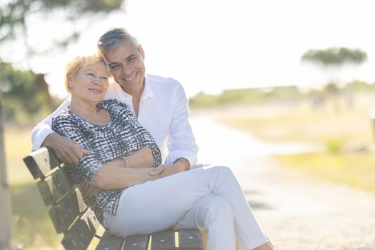 Senior couple enjoying retirement together while sitting on a park bench and embracing each other