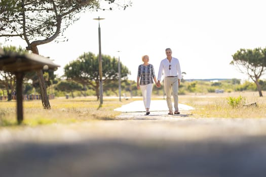 Happy retired couple enjoying a walk in a park on a sunny day