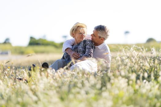 Senior couple relaxing in a meadow, embracing and enjoying retirement together