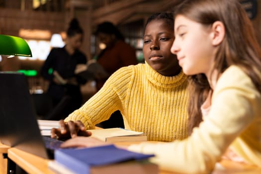 Young teen girls at a study desk attending virtual webinar class, focusing on e learning and academic activity via internet connection. Students chatting with their teacher on live web seminar.