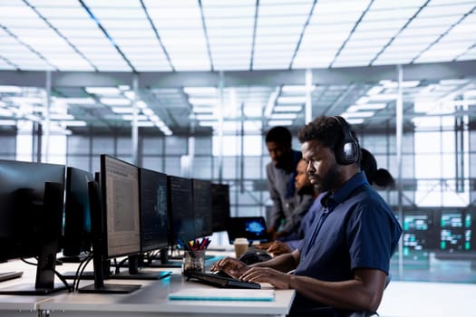 Man in data center workplace hearing songs in headset while using programming languages to build applications. Server hub software developer listening music, debugging code