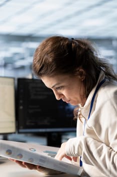 Management executive looking over paperwork in server farm to ensure compliance with industry standards and regulatory requirements. Close up of woman overseeing data center security protocols