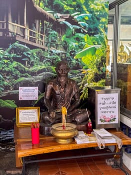 Bangkok, Thailand - November 11, 2024: Colorful shrine in Thailand features golden statue, floral offerings and intricate carvings symbolizing faith, spirituality and traditional Buddhist culture.