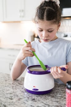 With focused attention, this budding culinary artist dips pretzels into a pot of melted chocolate, creating sweet delights in the warmth of a well-lit home kitchen.