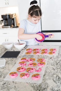 With focused attention, this budding culinary artist dips pretzels into a pot of melted chocolate, creating sweet delights in the warmth of a well-lit home kitchen.